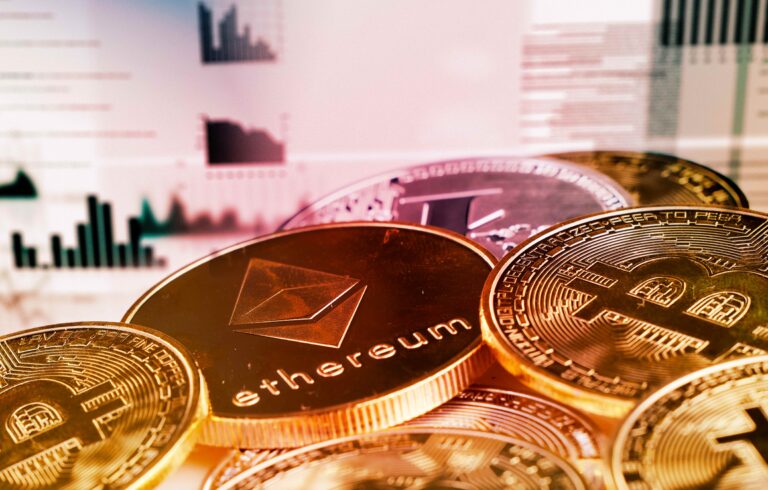 Monedas físicas de Bitcoin y Ethereum frente a gráficos bursátiles, representando la integración de criptomonedas en el sistema financiero global.