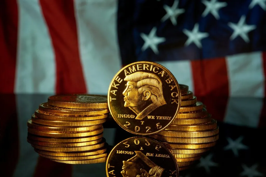 Moneda dorada con el perfil de Donald Trump y la leyenda Take America Back 2025 frente a la bandera de Estados Unidos, símbolo de la inclusión de criptomonedas en planes 401k.