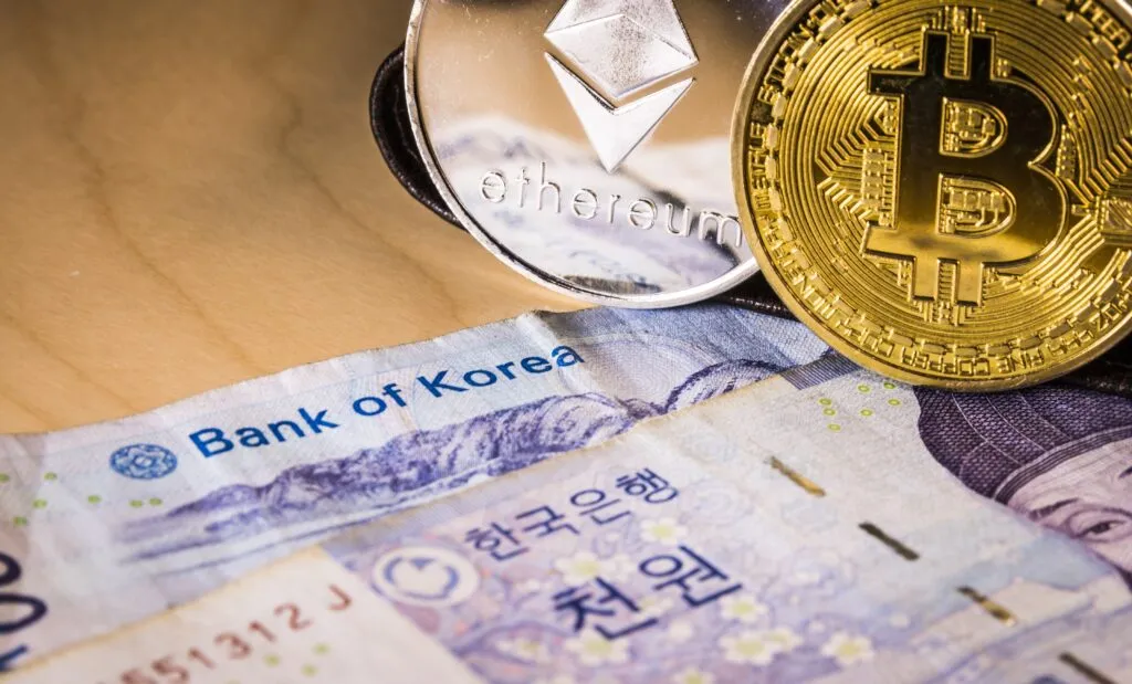 Monedas de Bitcoin y Ethereum sobre billetes del Banco de Corea, reflejando la regulación cripto y stablecoins respaldadas por el won en Corea del Sur