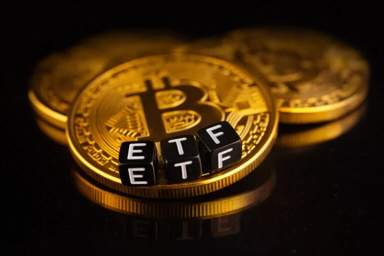 Imagen de monedas de bitcoin con fichas negras que forman la palabra ETF, usada en artículos sobre ETF cripto y correcciones del mercado.