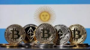 Monedas digitales de bitcoin sobre una mesa junto a billetes argentinos, representando las restricciones del Banco Central.